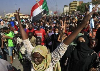 Sudanese protesters lift national flags as they rally on 60th Street in the capital Khartoum, to denounce overnight detentions by the army of government members, on October 25, 2021. - Armed forces detained Sudan's Prime Minister over his refusal to support their "coup", the information ministry said, after weeks of tensions between military and civilian figures who shared power since the ouster of autocrat Omar al-Bashir. (Photo by AFP)