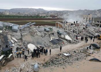 This aerial view shows residents helped by bulldozers, searching for victims and survivors in the rubble of collapsed buildings, following an earthquake in the town of Sarmada in the countryside of the northwestern Syrian Idlib province, early on February 6, 2023. - A 7.8-magnitude earthquake hit Turkey and Syria on February 6, killing hundreds of people as they slept, levelling buildings, and sending tremors that were felt as far away as the island of Cyprus and Egypt. (Photo by MUHAMMAD HAJ KADOUR / AFP)