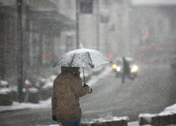 Man with umbrella during snow storm in the street